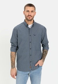 Blauw en wit geblokt overhemd met kraag, enkel borstzakje, opgerolde mouwen en een logo detail op de borst. Draagt met lichte jeans.