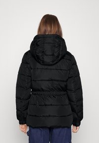 Černá péřová bunda s kapucí, obsahující prošívané části, elastický pas a přiléhavé manžety. Hladký materiál, minimalistický design.