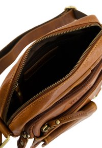 Brązowa skórzana torebka typu crossbody o gładkiej fakturze, z wieloma zamykanymi na zamek komorami i złotymi detalami.