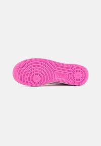 Vaaleanpunainen Nike-kenkien pohja, jossa on keskinäinen rengasmaiseen kuviot ja rakenne reunat valkoisella taustalla.