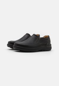 Schwarze Slipper aus strukturiertem Leder, mit kontrastierenden Nähten, einer abgerundeten Spitze und einer flexiblen Gummisohle.