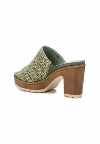 Ciabatta slide in tessuto verde intrecciato con tacco a blocco in legno, caratterizzata da una suola in gomma beige e un sottile dettaglio di cucitura lungo il bordo.