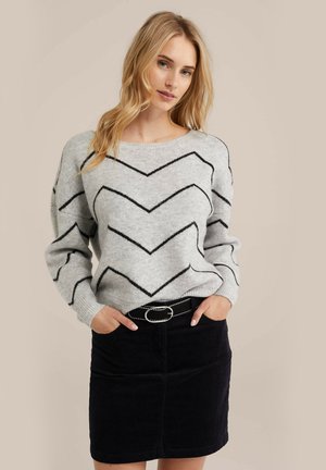Gray sweater with black zigzag pattern, round neckline, and dropped shoulders, paired with a black corduroy skirt and belt.