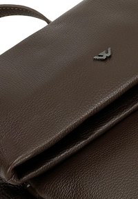 Bruine leren handtas met een gestructureerde afwerking, met een slank ontwerp en een klein reliëflogo. Inclusief schouderriem.