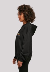 Black zip-up hoodie with a relaxed fit, featuring a multicolored logo on the chest and a kangaroo pocket; soft texture and adjustable hood.