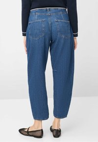 Blå denimbukser med en afslappet pasform, der har fem lommer og lynlåslukning. Stoffet har en subtil tekstur med en medium vask.