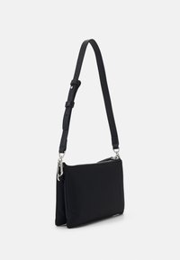 Black fabric crossbody bag with adjustable strap, silver hardware, two zip compartments, and a smooth texture. Minimalist design.