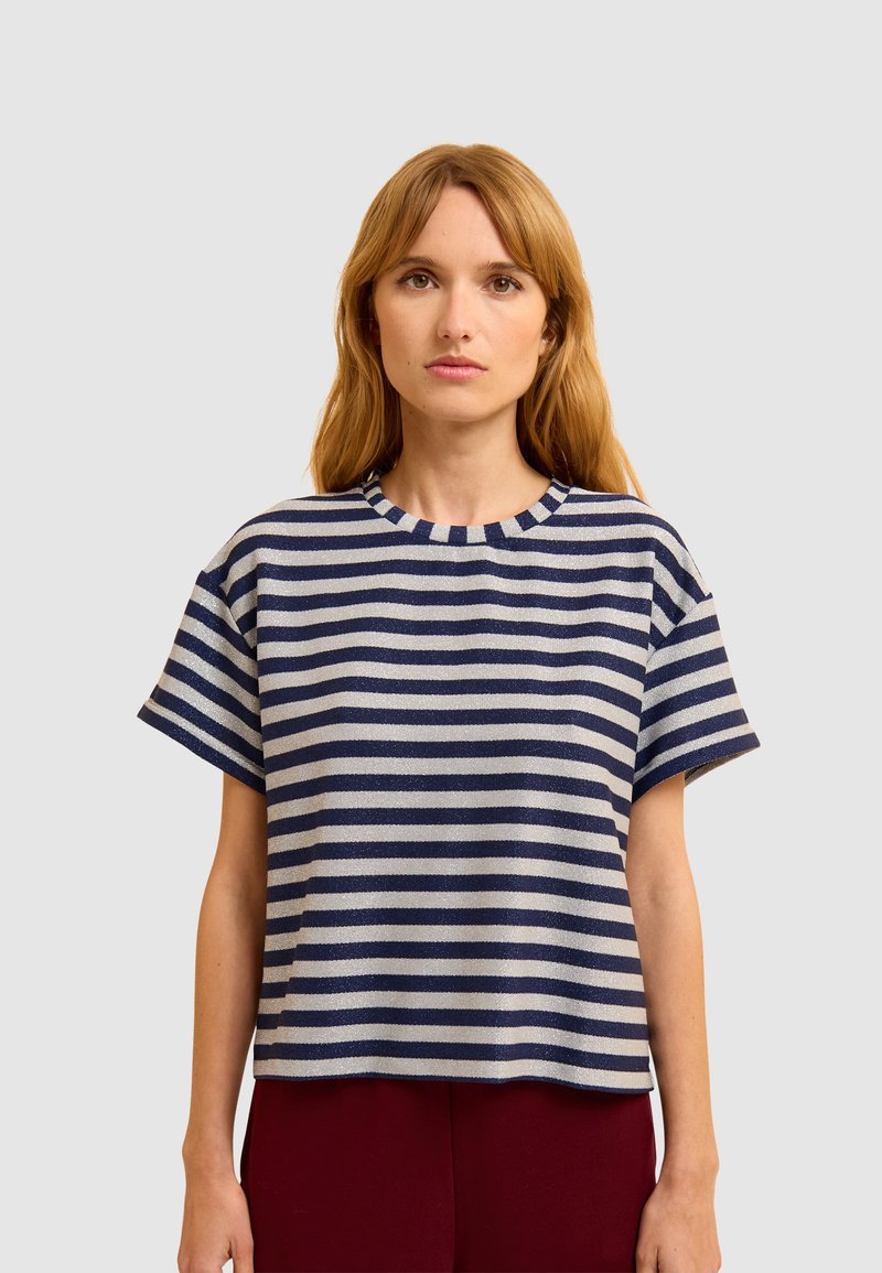 Camiseta a rayas con cuello redondo, mangas cortas, que presenta hilos en tonos marinos y metálicos en líneas horizontales alternas.