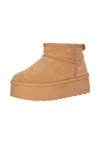 Botas de tobillo de ante beige con punta redondeada, bajo corte, suela plana y detalles de costura. Incluyen una lengüeta en la parte posterior.