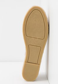 Sula av en sko i storlek 37 gjord i Spanien, med en ljusbrun gummibotten och strukturerade mönster i slitbanan.