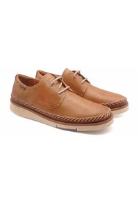 Chaussures en cuir marron avec des accents beige, présentant un design cousu et des semelles en caoutchouc crème. Les lacets sont de couleur brun clair ; forme de bout arrondi.