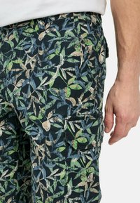 Cargo-Shorts aus Baumwolle mit dunklem Hintergrund und einem kontrastierenden, mehrfarbigen Blattform-Muster. Enthält eine seitliche Taschendetail.