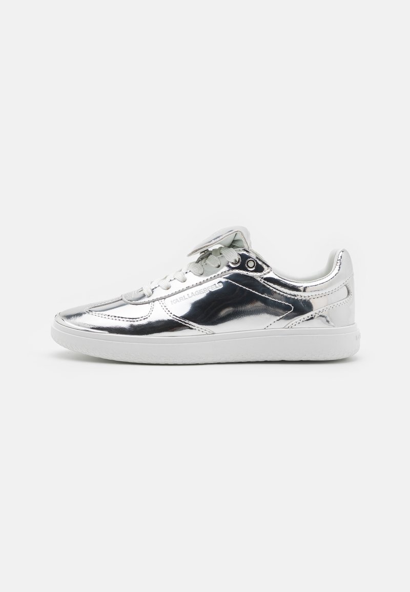 Metallic silver sneaker with smooth texture, flat white sole, round toe, and white laces; features logo detail on the side and tongue.