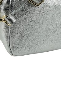 Silberne metallic Handtasche mit strukturierter Oberfläche, ausgestattet mit einem goldfarbenen Hardware-Akzent und abnehmbarem Schulterriemen. Rechteckige Form mit flachem Boden.