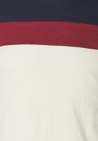 Horisontella marinblå, vinröda och vita ränder på tyg, som visar en närbild av ett textilmönster.