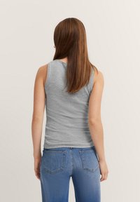 Gray sleeveless shirt made of soft fabric, featuring a round neckline and a fitted shape, paired with blue denim jeans.