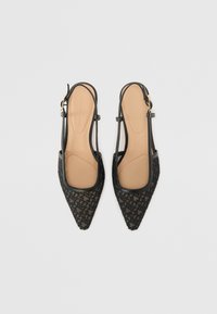 Paire de ballerines slingback noires à bout pointu avec motif géométrique texturé et semelles intérieures couleur caramel sur fond gris clair.