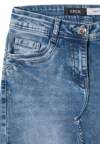 Jeans de mezclilla azul claro con un lavado desgastado, que cuentan con un cierre de cremallera, botón y un diseño tradicional de cinco bolsillos. Detalle de pequeño bolsillo en la parte delantera.