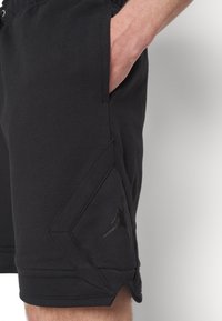 Svarta idrottsshorts i bomullsblandning med en texturerad yta, med en pr äglad logotyp och vinklade fickdetaljer.