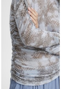 Långärmad topp i lätt, strukturerat tyg med ormmönster i beige och grått. Har rynkade sidor och mjuk silhuett.