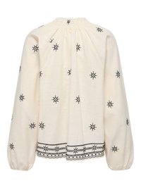 Blouse crème à manches longues avec encolure froncée, broderie géométrique noire dispersée et le long de l'ourlet et des poignets.