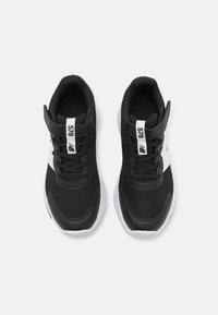 Chaussures de sport noires avec tige en mesh, accents blancs et lacets ajustables. Présentent une semelle en caoutchouc et une étiquette de marque sur la languette.
