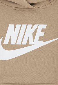 Hoodie beige avec un logo "NIKE" en blanc audacieux et le swoosh. Tissu doux avec une texture lisse, conçu pour le confort et le style décontracté.