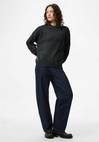 Mörkgrå tröja i texturerat tyg med rund hals och ribbad fåll. Matchas med löst sittande mörka jeans och svarta stövlar.