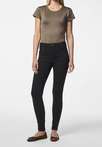 Ruskea istuva paita, mustat slim-fit-housut ja eläinkuosilla varustetut ballerinat. Sileä tekstiili, jossa on lyhyet hihnat ja pyöreä pääntie.