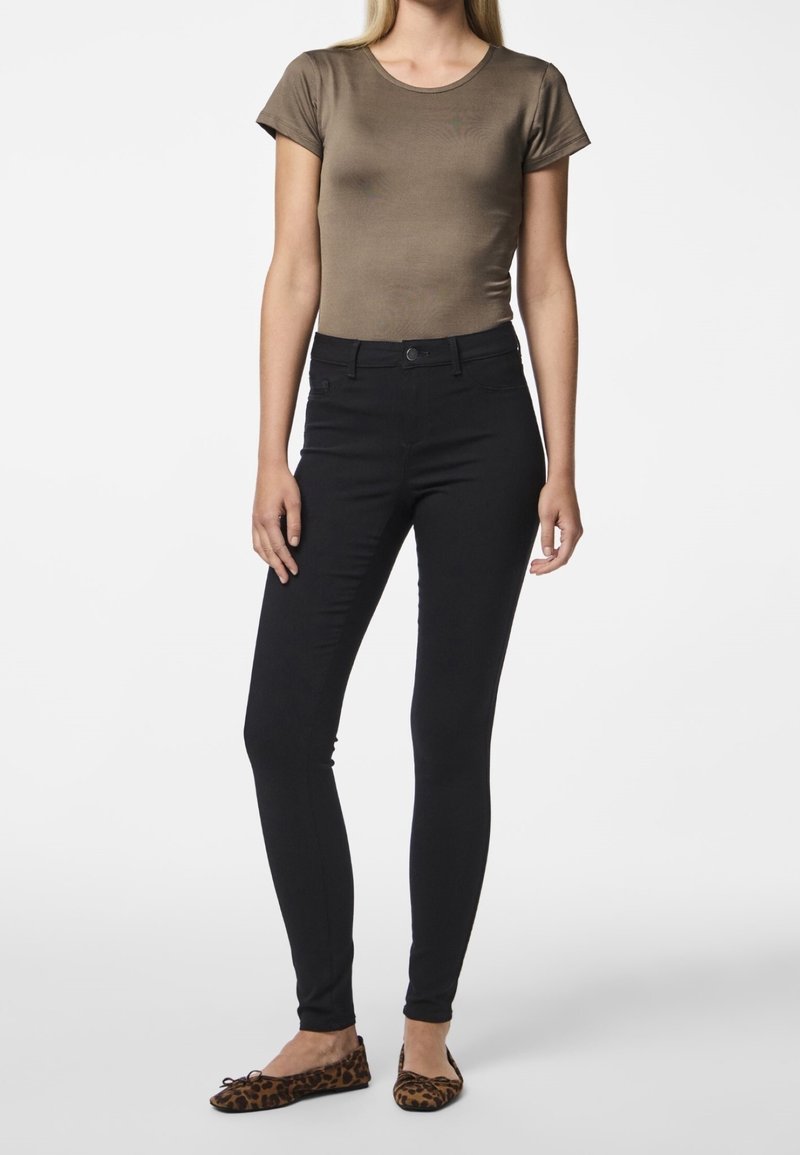 Ruskea istuva paita, mustat slim-fit-housut ja eläinkuosilla varustetut ballerinat. Sileä tekstiili, jossa on lyhyet hihnat ja pyöreä pääntie.