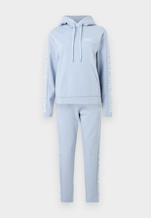 Gaiši zils kapuces džemperis un atbilstošas sporta bikses ar baltu Emporio Armani EA7 zīmi uz piedurknēm un bikses kājām, priekšpusē kapuces džempera kabata.