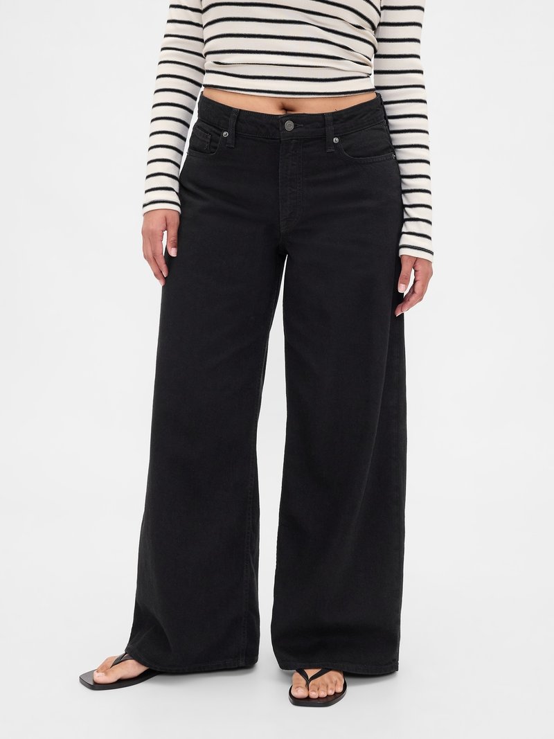 Crne traperice širokih nogavica s visokim strukom, dizajnom s pet džepova i srednje teškom teksturom tkanine, uparene s prugastim kratkim topom.