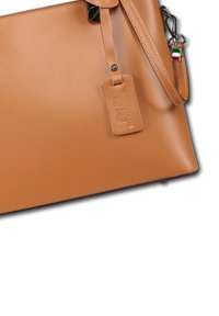 Tan genuine leather handbag with stitched strap, leather tag embossed "Genuine Leather Made in Italy," and small Italian flag charm.