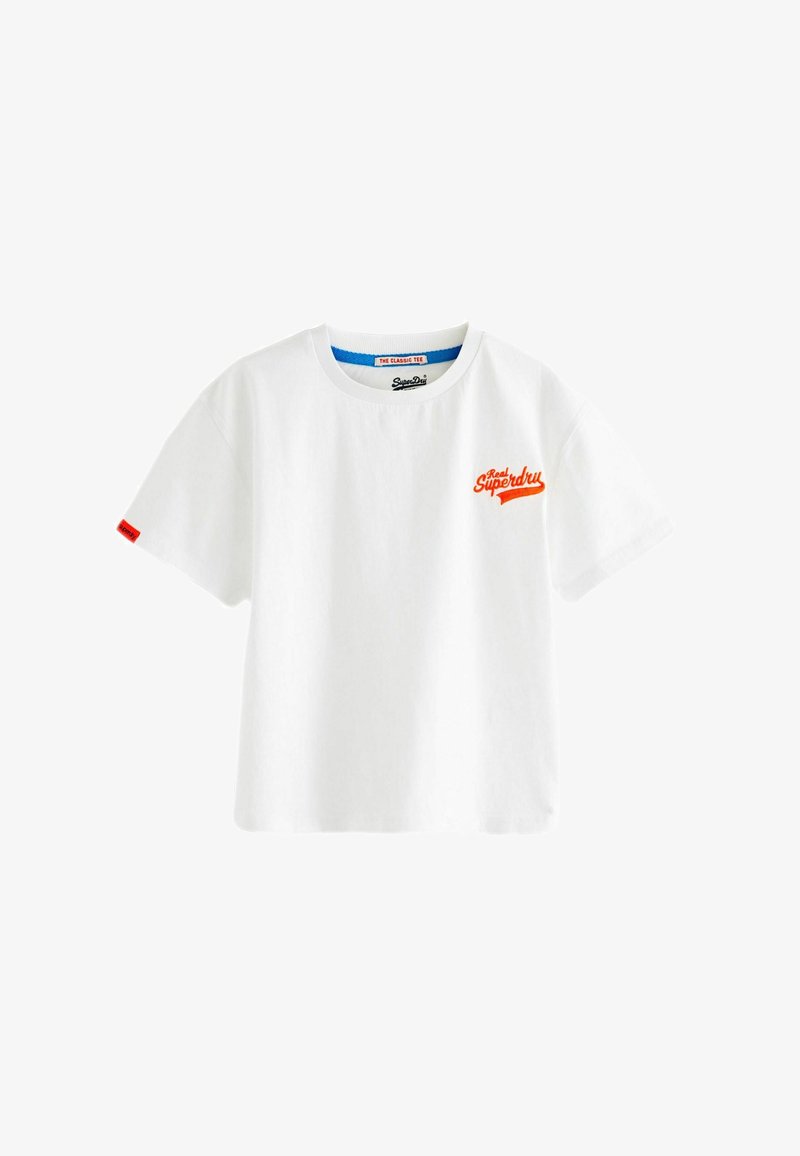 Camiseta de algodón blanca con cuello redondo, mangas cortas, que presenta un logotipo bordado naranja en el lado izquierdo del pecho y una etiqueta roja en la manga.