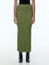 Groene gebreide maxi-rok met een geribbeld textuur, hoge taille en een getailleerde silhoutte, gecombineerd met zwarte enkellaarsjes met hak.