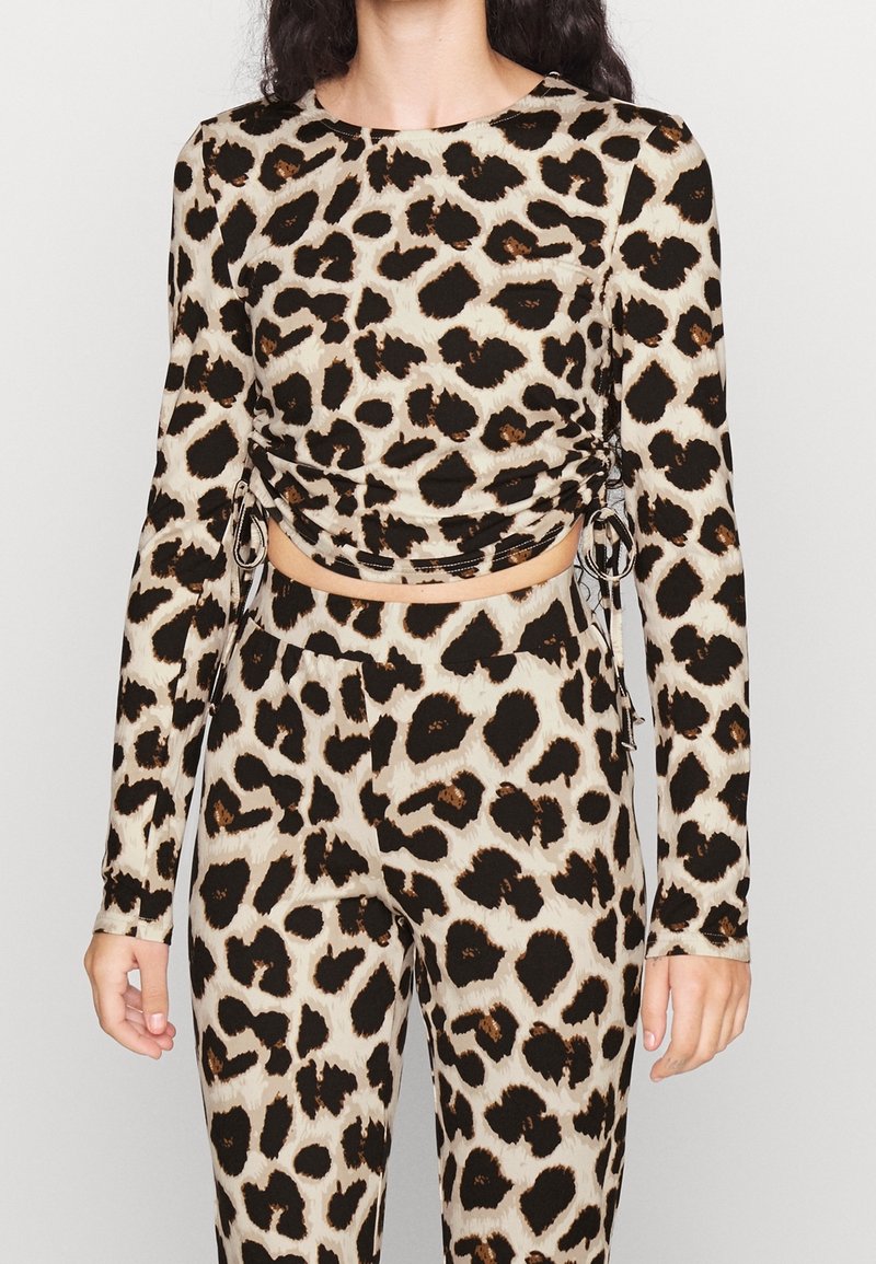 Długi rękaw top wykonany z miękkiego materiału, z beżową bazą i czarno-brązowym wzorem w panterkę, z marszczeniami po bokach i regulowanymi sznurkami.