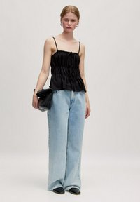 Zwarte satijnen peplumtop met spaghettibandjes, gecombineerd met lichtblauwe wijde jeans en een zwarte clutch, met een casual, losse pasvorm.