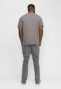 Gray short-sleeve t-shirt with a round neckline paired with gray pants. Pants feature two rear pockets with stitching details and cuffed ankles.