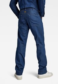 Donkerblauwe spijkerwerkbroek met rechte pijpen, verstevigde stiksels, dubbele achterzakken en een klein merklabel op de tailleband.