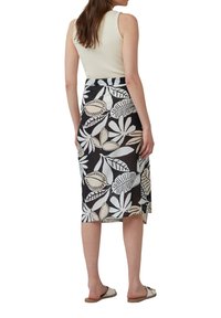 Middellange, zwarte rok met een witte bladeren- en plantenpatroon. Gemaakt van lichtgewicht stof met een licht doorschijnende textuur. De zoom heeft zijsplitsingen.