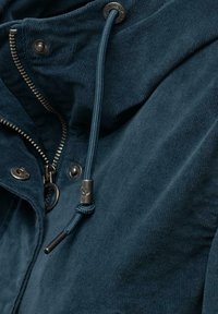 Laivastonsininen corduroy-takki, jossa on vetoketjukiinnitys, metalliset yksityiskohdat ja nyörisäätöinen huppu teksturoidulla pinnalla.