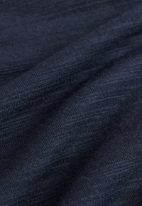 Tessuto blu scuro con trama testurizzata e motivo a maglia morbida, che mostra variazioni sottili di tonalità e una finitura liscia, adatto per abbigliamento o rivestimenti.