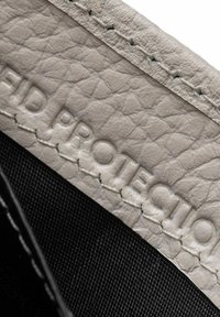 Cuero texturizado gris con un interior de tela negra, presenta el texto grabado "PROTECCIÓN RFID" y costuras contrastantes en blanco.