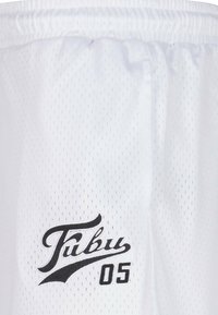 Hvite mesh-shorts med små åpninger for pusteevne. Har en svart brodert logo "Fubu 05" på venstre forside. Elastisk midje.