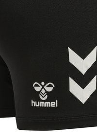 Zwarte sportbroekjes gemaakt van rekbaar materiaal met het witte Hummel-logo en chevron-accenten aan de zijkant. Glad textuur, figuurvormende ontwerp.