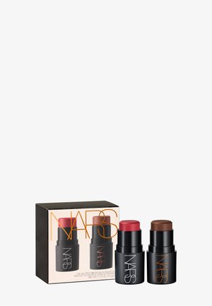To NARS mini sminke-stifter, en rød blush og en brun kontur, ved siden av deres svarte og gullmerkede emballasjeboks.