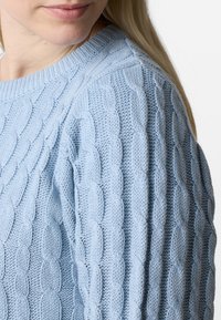 Hellesblaues Strickpullover mit einem strukturierten Kabelmuster, mit einem runden Halsausschnitt und gerippten Bündchen.