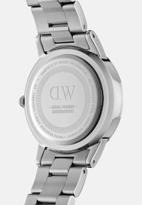 Stainless steel watch with a polished finish, featuring a round case back engraved with brand details, model number, and water resistance information.
