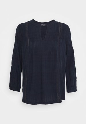 Blusa de manga larga azul marino con escote redondo con abertura y detalles sutiles de encaje vertical en la parte delantera y mangas.