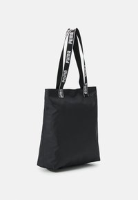 Zwarte stoffen tote bag met een rechthoekige vorm, lange handvatten met "PUMA" branding en een soepele, matte textuur.